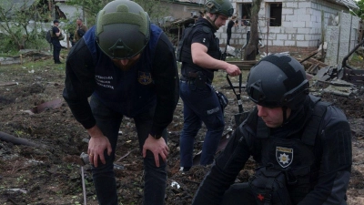 Ein ukrainischer Polizeibeamter und ein Staatsanwalt für Kriegsverbrechen inspizieren Bruchstücke einer Gleitbombe vor einem beschädigten Haus nach einem russischen Luftangriff auf ein Wohnviertel. (Foto: Evgeniy Maloletka/AP/dpa)