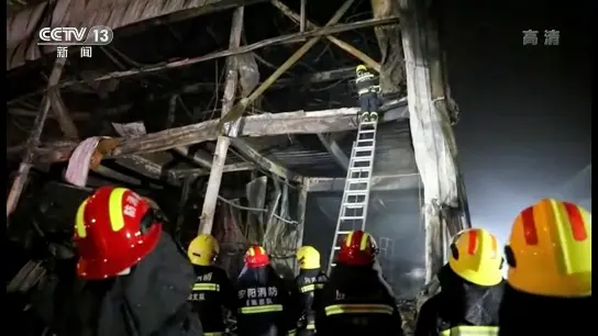Auf diesem Standbild aus Videoaufnahmen des chinesischen Fernsehsenders CCTV klettern Rettungskräfte mit einer Leiter in die Fabrik. (Foto: Uncredited/CCTV/AP/dpa)