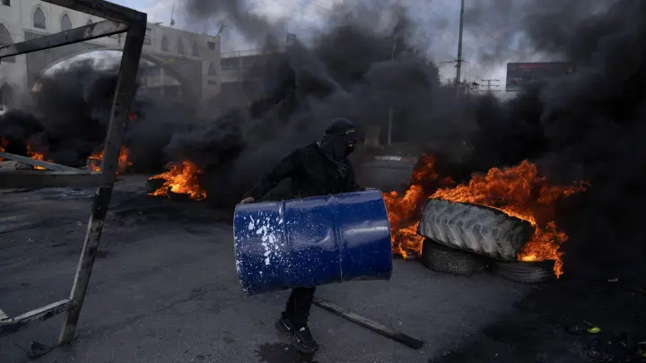 Palästinensische Demonstranten blockieren nach dem Einsatz des israelischen Armee in Jericho eine Straße mit brennenden Reifen. (Foto: Nasser Nasser/AP/dpa)