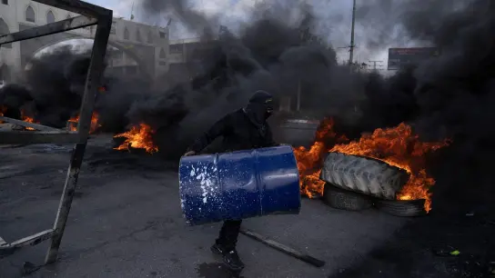 Palästinensische Demonstranten blockieren nach dem Einsatz des israelischen Armee in Jericho eine Straße mit brennenden Reifen. (Foto: Nasser Nasser/AP/dpa)
