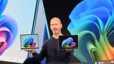 Microsoft-Manager Brett Ostrum zeigt ein Notebook und ein Tablet der hauseigenen Marke Surface, die auf den Einsatz Künstlicher Intelligenz ausgerichtet sind. Microsoft will Windows-PCs fit für die KI-Ära machen. (Foto: Andrej Sokolow/dpa)