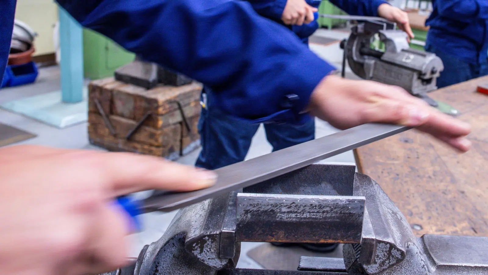 Lehrlinge arbeiten mit der Metallfeile an Schraubstöcken in einer Lehrwerkstatt in Wismar. (Foto: Jens Büttner/dpa)