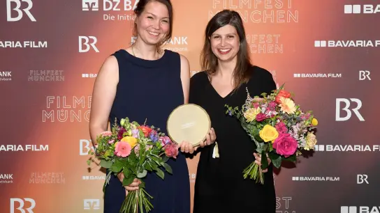 Die Preisträgerinnen in der Kategorie Produktion, Laura Klippel (l) und Britta Strampe, halten ihren Preis für „The Ordinaries“. (Foto: Felix Hörhager/dpa)