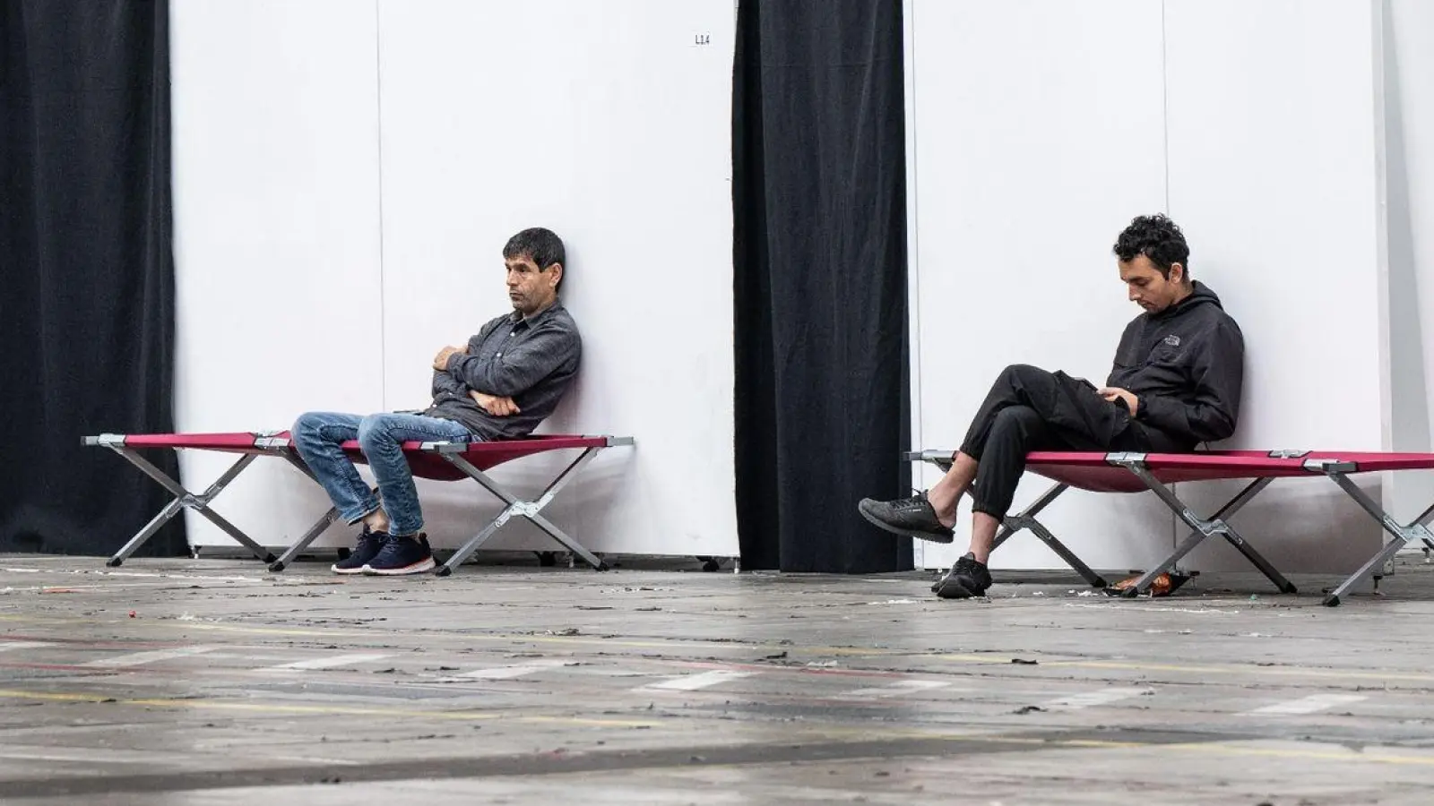 Geflüchtete sitzen auf Feldbetten in einer Massenunterkunft in Frankfurt: Viele Geflüchtete wünschen sich mehr Hilfe in Asyl- und Flüchtlingsfragen. (Foto: Boris Roessler/dpa)