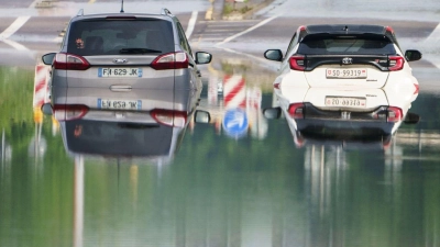 Zwei Autos stehen unter einer Saarbrücke im Stadtteil Schönbach im Hochwasser. (Foto: Andreas Arnold/dpa)
