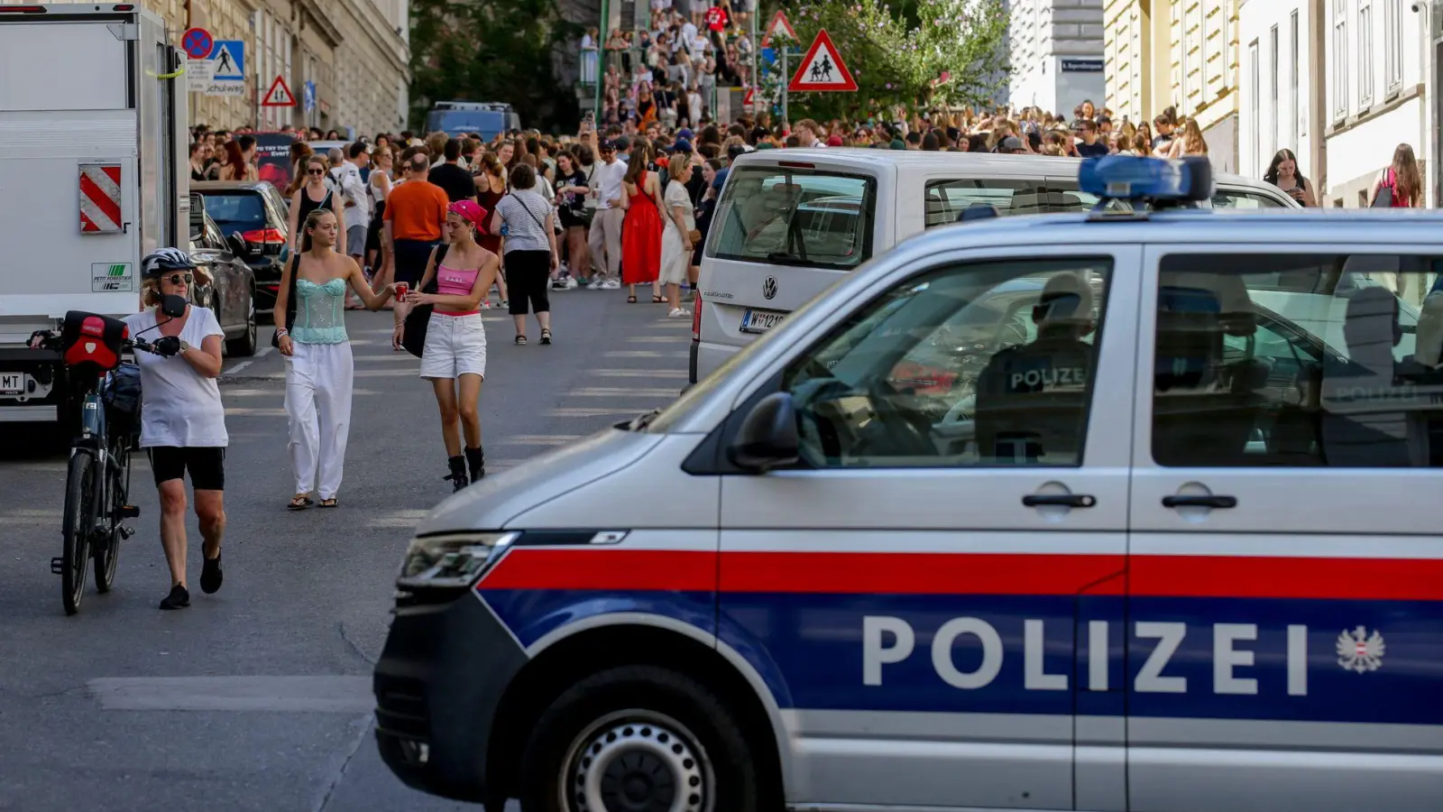 Ein Polizeiauto steht in der Nähe von versammelten „Swifties“, nachdem im Sommer 2024 Konzerte abgesagt wurden aus Angst vor einem Terroranschlag. (Archivbild)  (Foto: Heinz-Peter Bader/AP/dpa)