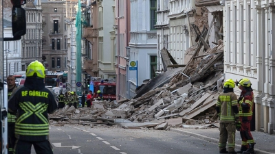 Einsatzkräfte von Polizei und Feuerwehr stehen in der Nähe eines eingestürzten Hauses in Görlitz. Als Ursache vermutet man eine Gasexplosion. (Foto: Paul Glaser/dpa/dpa-tmn)