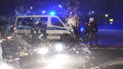 Polizeibeamte stehen in der Silvesternacht in Berlin hinter explodierendem Feuerwerk (Symbolbild). „Auch in Deutschland sind an bestimmten Orten solche Krawallexzesse denkbar“, sagt Polizei-Gewerkschafter Jochen Kopelke. (Foto: Julius-Christian Schreiner/TNN/dpa)