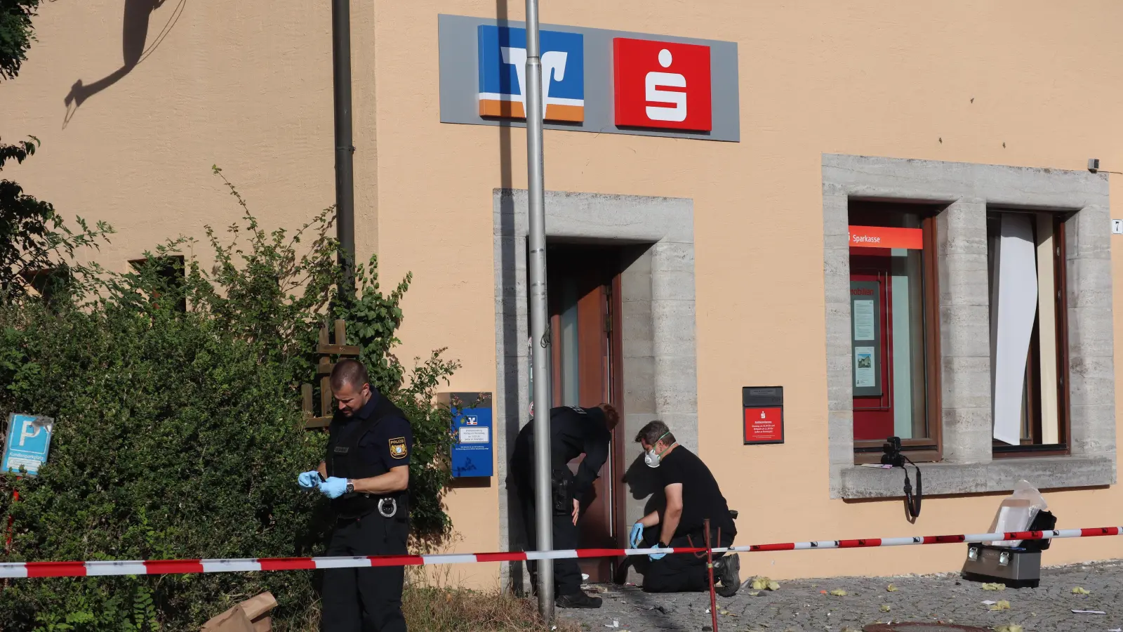 Am Morgen nach der Sprengung suchen Polizeibeamte am Tatort nach Spuren. In der Filiale arbeiten Sparkasse und VR-Bank zusammen. (Foto: Gudrun Bayer)