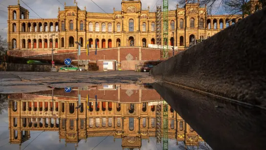 Der Bayerische Landtag spiegelt sich nach einem Regenschauer in einer Pfütze auf der Maximiliansbrücke. (Foto: Peter Kneffel/dpa)