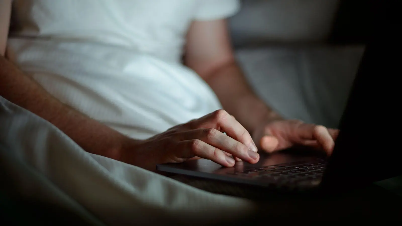 Gemütlich im Bett zu arbeiten ist verlockend, doch Notebooks sollten auf festen und ebenen Unterlagen stehen, damit die Luftzirkulation nicht behindert wird. (Foto: Sina Schuldt/dpa/dpa-tmn)