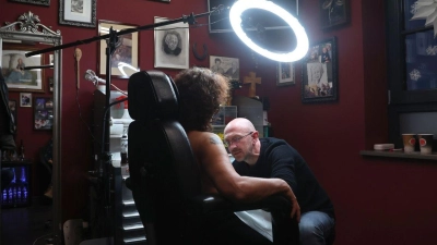 Tattoo-Künstler Andy Engel (r) tätowiert der Brustkrebspatientin Anja D. eine Brustwarze. (Foto: Karl-Josef Hildenbrand/dpa)