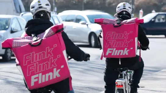 Zwei Fahrradkuriere mit Rucksäcken des Lebensmittel-Lieferdienstes Flink. (Foto: Sebastian Kahnert/dpa-Zentralbild/dpa)