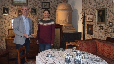 Eines der Epochenzimmer im Fränkischen Museum Feuchtwangen bietet einen Einblick in die Wohnkultur des Biedermeiers. Der Vorsitzende des Vereins für Volkskunst und Volkskunde, Bürgermeister Patrick Ruh, und Museumsleiterin Dr. Uta Karrer freuen sich auf die anstehende Sonderschau anlässlich „100 Jahre Dauerausstellung”. (Foto: Jasmin Kiendl)