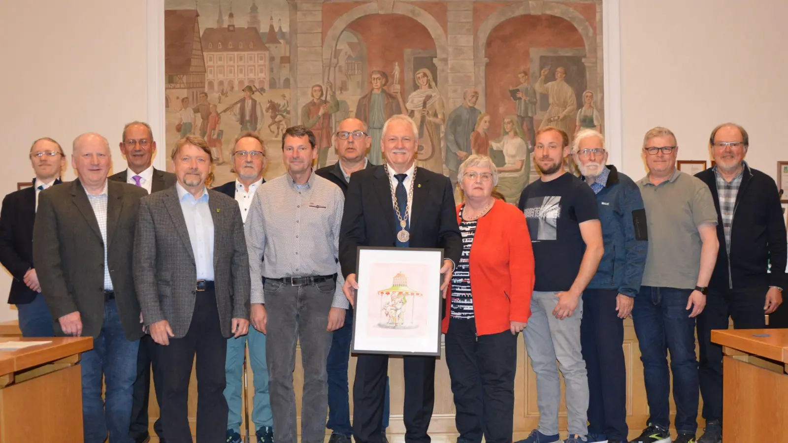 Zum Abschiedsbild stellten sich die scheidenden Ortssprecher und Stadträte und nahmen den in den Ruhestand wechselnden Bürgermeister in ihre Mitte. Dieser präsentierte dabei das Geschenk seiner SPF-Fraktion: Ein Bild des Neustädter Künstlers Peter Papst, auf dem Klaus Meier auf einer Karussellfigur sitzend mit dem Text „Drei Runden sind genug” zu erkennen ist.  (Foto: Patrick Lauer)