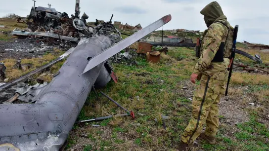 Ein ukrainischer Soldat betrachtet auf der Schlangeninsel im Schwarzen Meer ein zerstörtes russisches Militärflugzeug. (Foto: Michael Shtekel/AP/dpa)