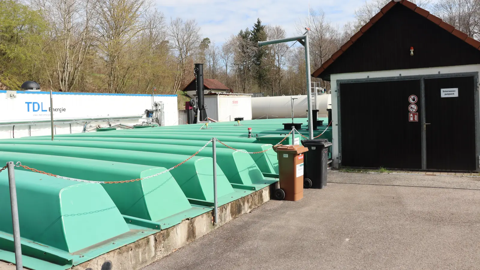 Unter den türkisfarbenen Abdeckungen wird das Sickerwasser aus der Deponie im Dienstfeld bei Aurach zwischengespeichert. Im Hintergrund ist die momentan eingesetzte Übergangs-Reinigungsanlage zu sehen, die aber in absehbarer Zeit ersetzt werden soll. (Foto: Thomas Schaller)