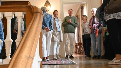 Karin Reichmeyer (links) und der Enkel von Kurt von Seckendorff (2.von links) führen durchs Neue Schloss. Im Eingangsbereich ist fast auf Höhe der Zimmerdecke der Grundstein untergebracht. (Foto: Judith Marschall)