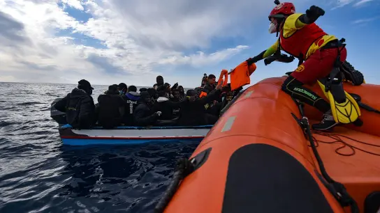 Mitglieder der NGO Open Arms helfen Migranten, die in einem Holzboot vor der Küste Libyens im Mittelmeer aufgebrochen sind. (Foto: Antonio Sempere/EUROPA PRESS/dpa)