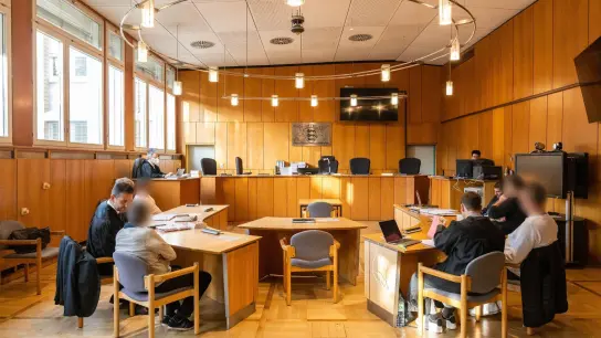 Vier Angeklagte sitzen mit ihren Verteidigern im Vorfeld der Verhandlung im Saal des Landgerichts Offenburg. (Foto: Philipp von Ditfurth/dpa)