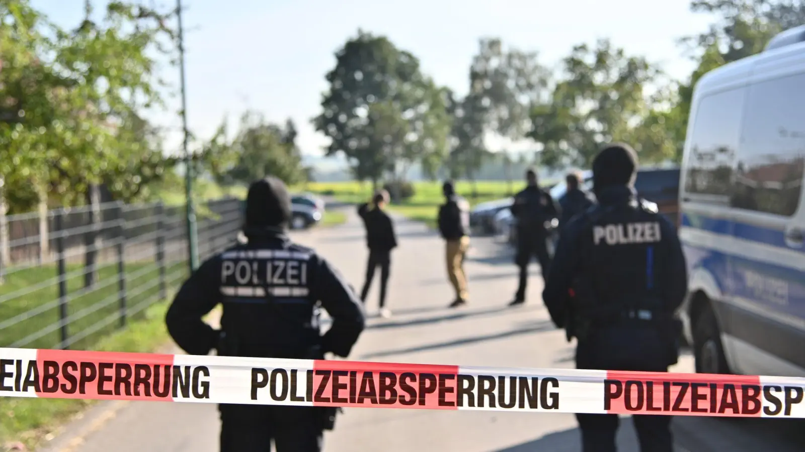 Einsatzkräfte der Polizei stehen hinter einer Polizeiabsperrung nach einer Razzia in Hesselbronn. (Foto: Jan-Philipp Strobel/dpa)