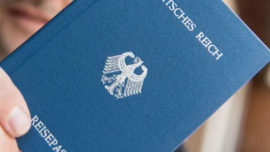Ein Mann hält ein Heft mit dem Aufdruck „Deutsches Reich Reisepass“ in der Hand. (Foto: Patrick Seeger/dpa/Archiv)