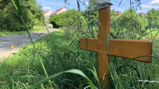 „Daniel“ steht auf einem Holzkreuz und erinnert an den 24-Jährigen, der auf dem Radweg starb. (Foto: Gregor Bauernfeind/dpa/Archivbild)