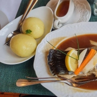 Thüringer Klöße werden im Resort Schloss Auerstedt zum Karpfen mit Bratensoße serviert.  (Foto: Andreas Drouve/dpa-tmn)