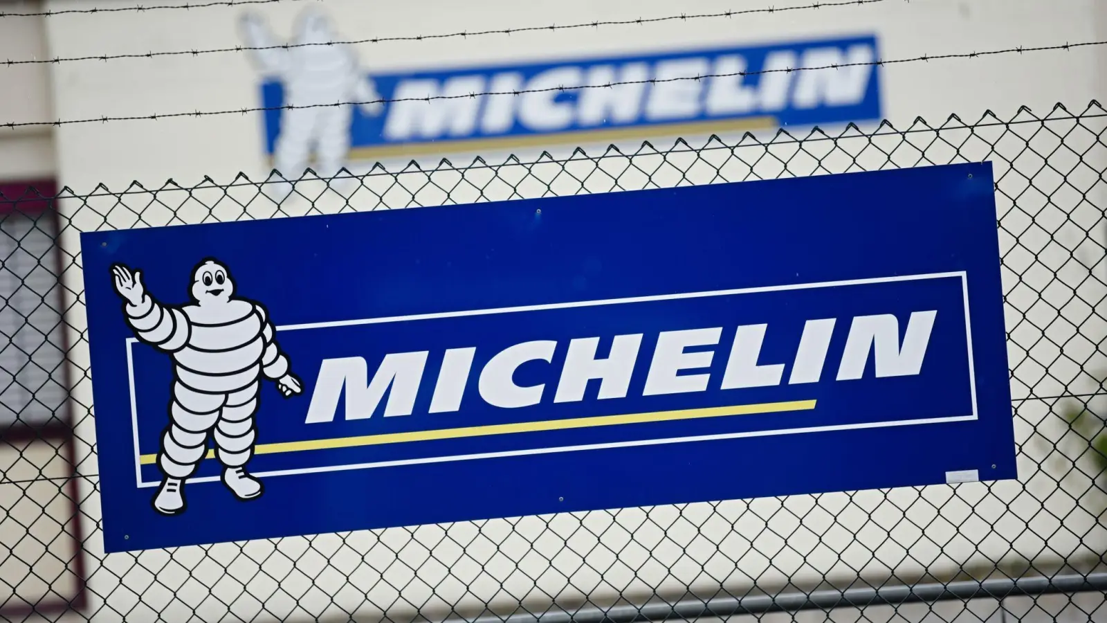 Vor dem Michelin-Werk in Hallstadt ist ein Banner mit dem Firmenlogo an einem Zaun zu sehen. (Foto: Nicolas Armer/dpa)