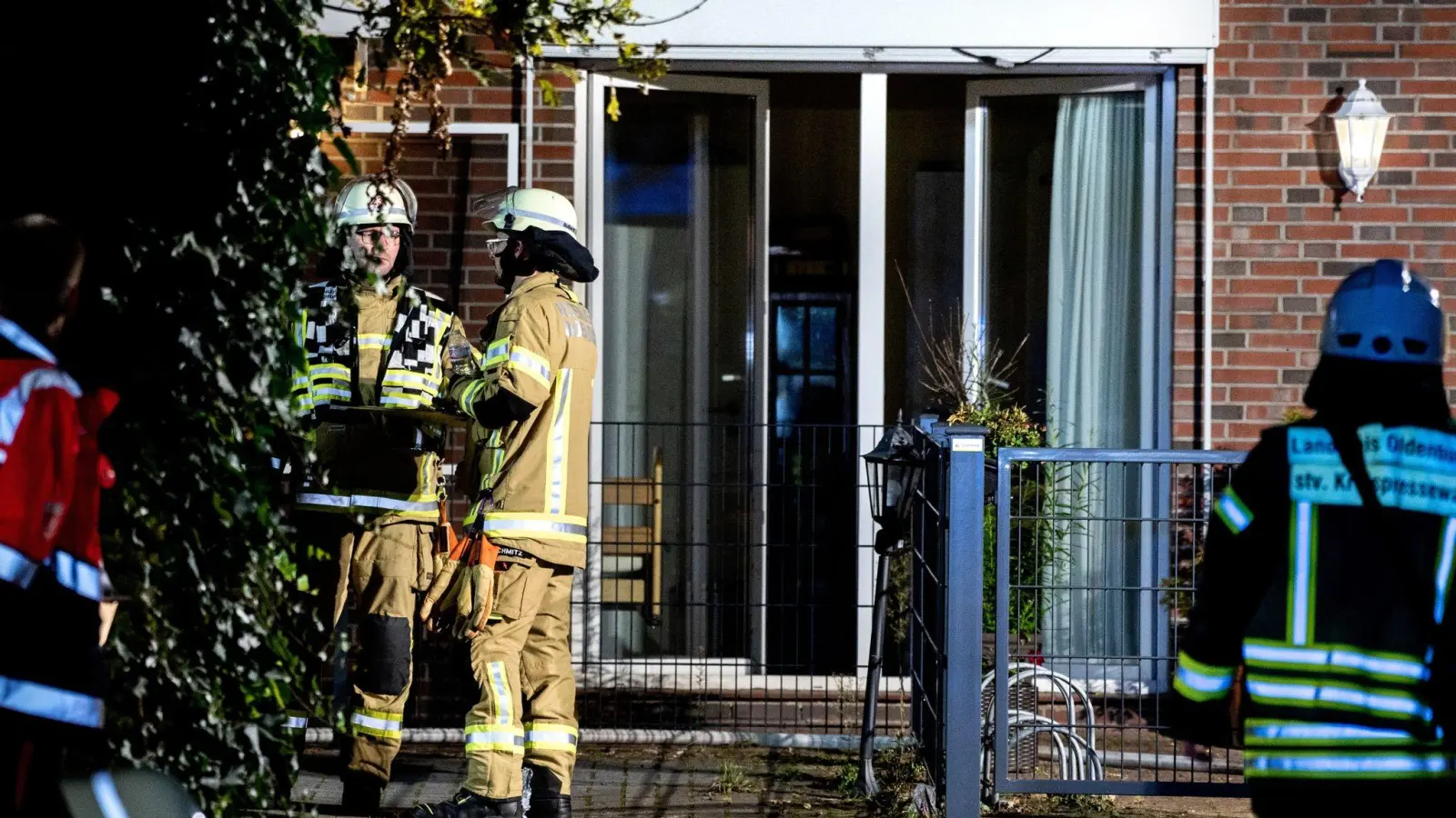 Einsatzkräfte der Feuerwehr stehen vor dem in Brand geratenen Altenheim in Wardenburg. (Foto: Hauke-Christian Dittrich/dpa)