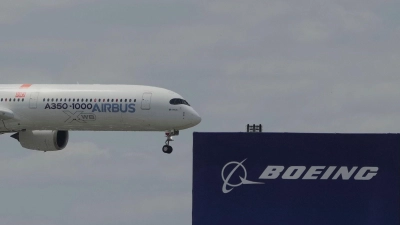 Die zwei großen Konkurrenten: Ein Airbus fliegt bei einer Vorführung auf der Luftfahrtmesse Salon du Bourget an einem Logo von Boeing vorbei. (Foto: Michel Euler/AP/dpa)