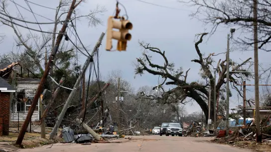 Autos fahren vorsichtig an umgestürzten Bäumen und Stromleitungen in Selma vorbei. (Foto: Stew Milne/AP/dpa)