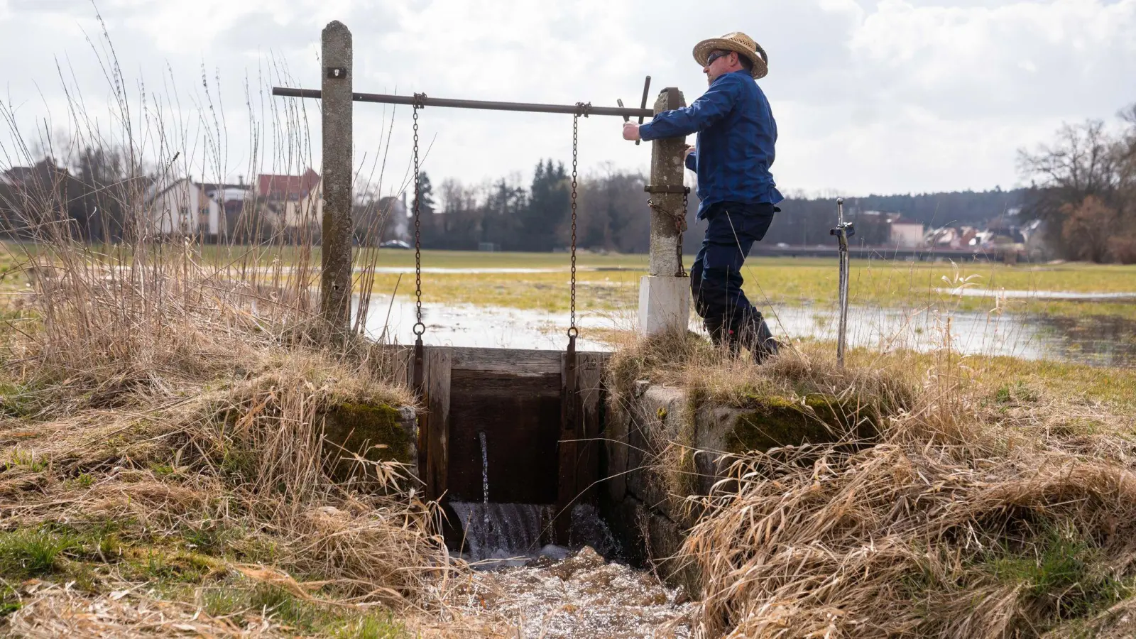 Der Wässerer Jürgen Zwingel öffnet eine Schleuse eines Wässergrabens im Ortsteil Reichelsdorf. (Foto: Nicolas Armer/dpa)