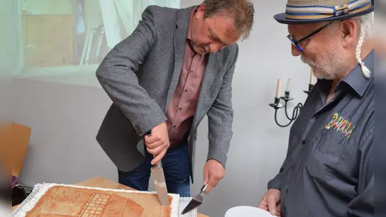 Uehlfelds Bürgermeister Detlef Genz (links) schneidet die Torte – stilecht mit Torhaus – gekonnt an. Der Bänkla-Vorsitzende Walter Kirsch nahm das erste Stück in Empfang. (Foto: Johannes Zimmermann)
