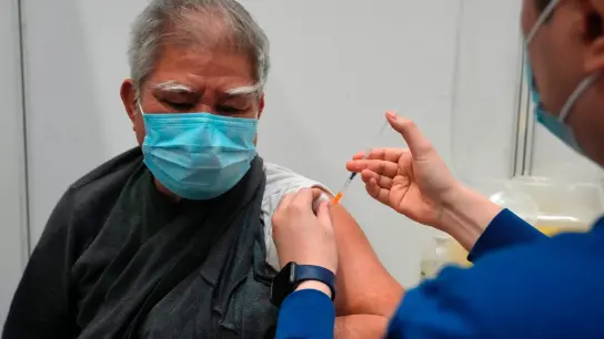 Hui Ngai-seng erhält in einem Impfzentrum in Hongkong seine erste Dosis des chinesischen Corona-Impfstoffs Sinovac. (Foto: Kin Cheung/AP/dpa)