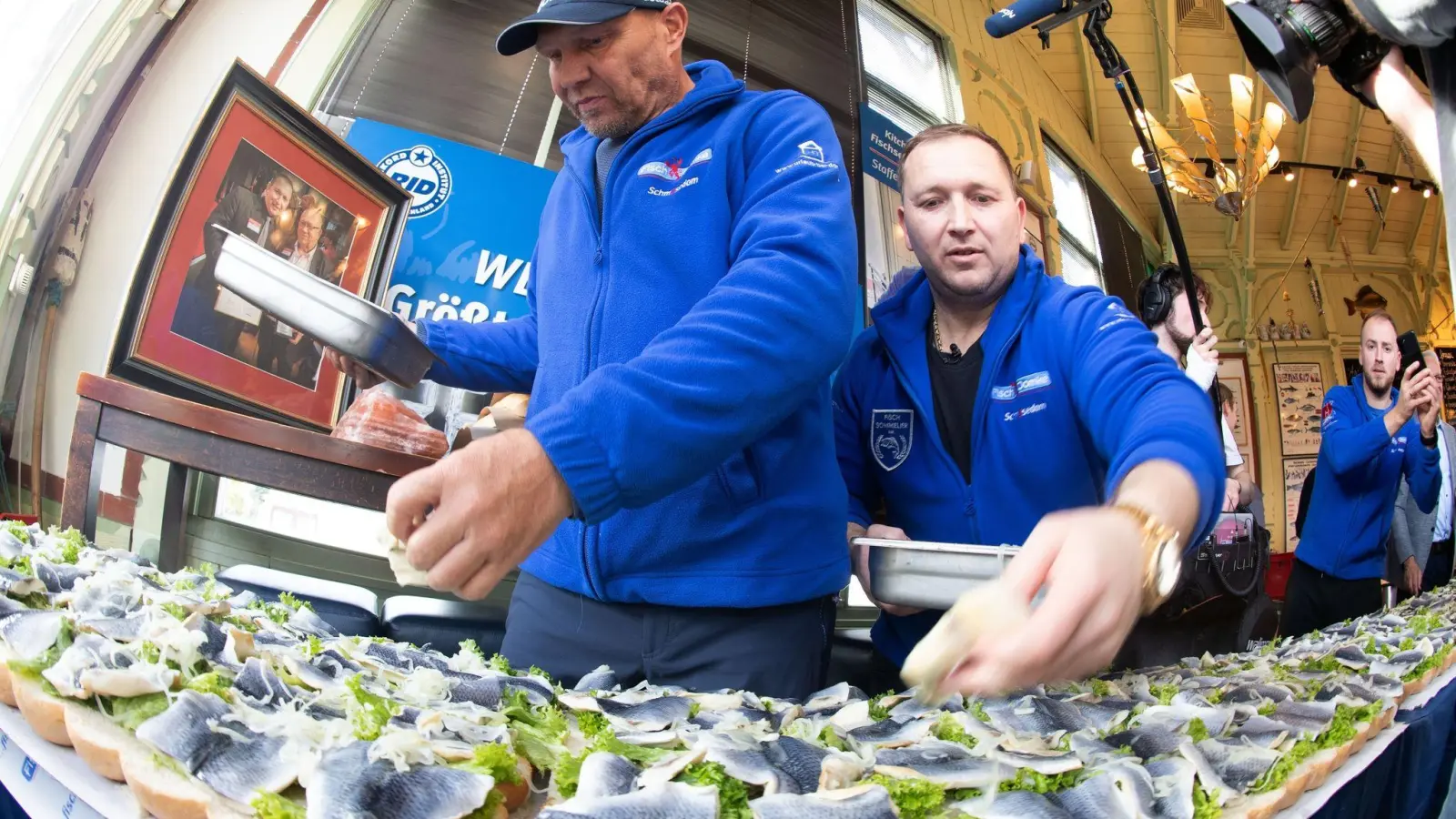 Axel Schulz, ehemalige Profiboxer (l-r), und André Domke, Fischsommelier und -händler, belegen das gigantische Fischbrötchen mit Salat, Fisch und Zwiebeln. (Foto: Stefan Sauer/dpa)