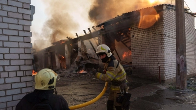 Rettungskräfte löschen ein Feuer in einer Kiewer Autowerkstatt, die durch einen russischen Angriff beschädigt wurde. (Foto: Evgeniy Maloletka/AP/dpa)