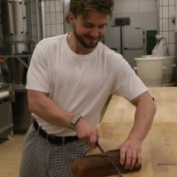 Maximilian Wimmer halbiert in seiner Bäckerei das Brot mit dem Messer und wiegt nicht nach. (Foto: Alexander Rausch)