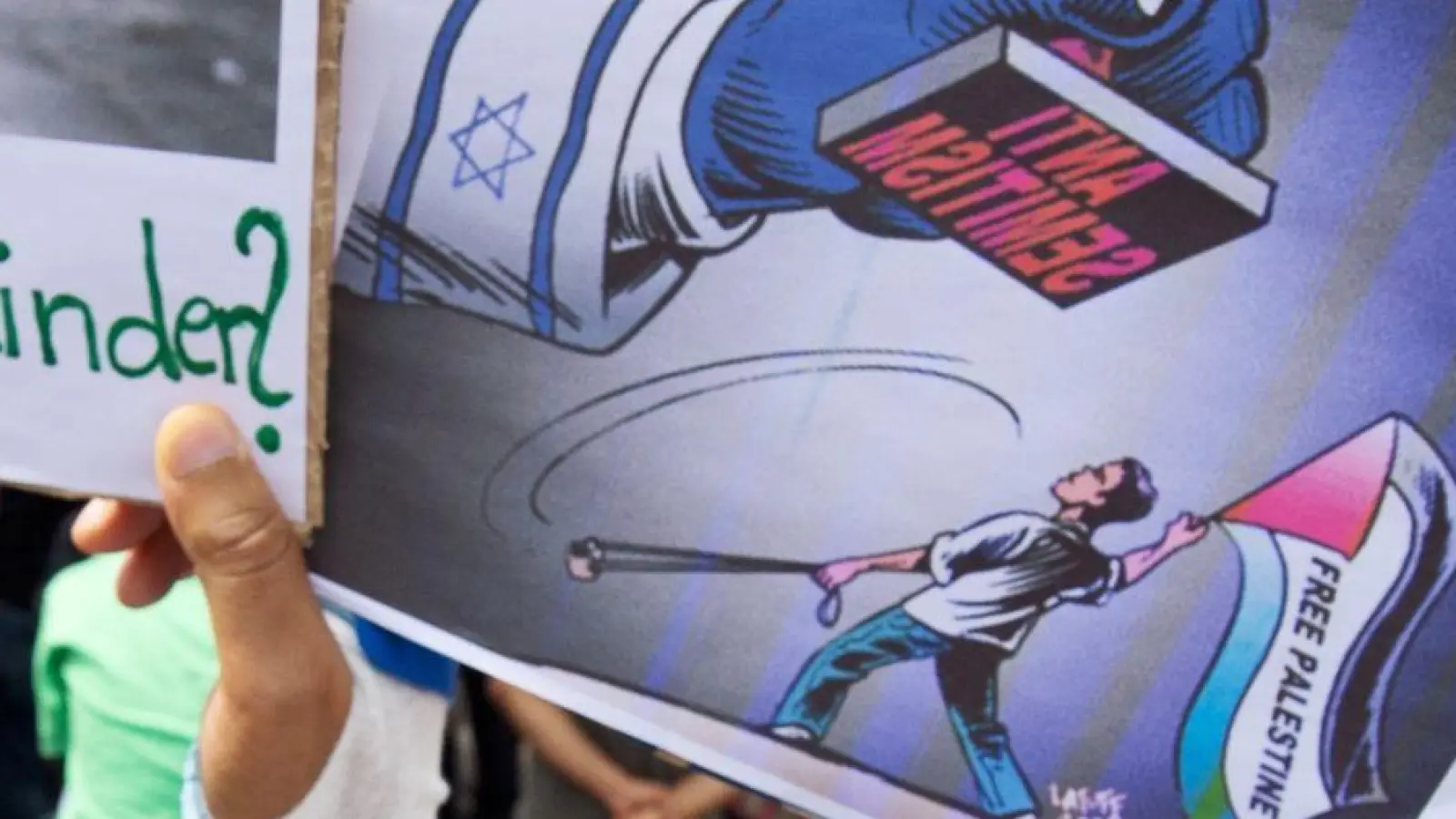 Ein Junge hält ein Plakat hoch, auf dem ein propalästinensischer Demonstrant unter einem Stempel mit der Aufschrift „Anti Semitismus“ steht. (Foto: picture alliance / dpa)