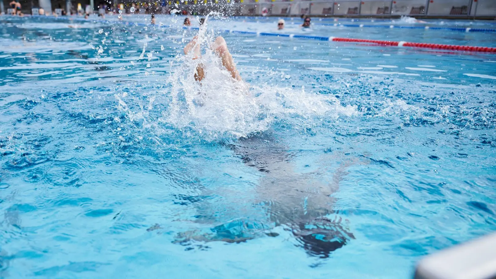 Ein Kind springt in einem Schwimmbad ins Becken. (Foto: Annette Riedl/dpa/Symbolbild)