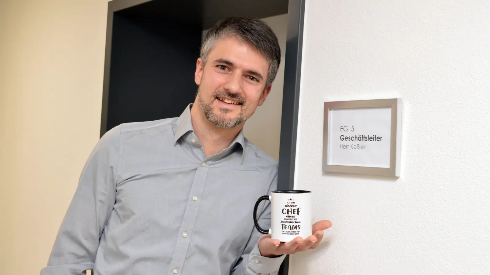 Umgezogen ins Geschäftsstellenleiter-Zimmer ist Andreas Keßler bereits, auch das Schild ist schon getauscht. Hier posiert der 38-Jährige mit seiner neuen Lieblingstasse. (Foto: Johannes Zimmermann)