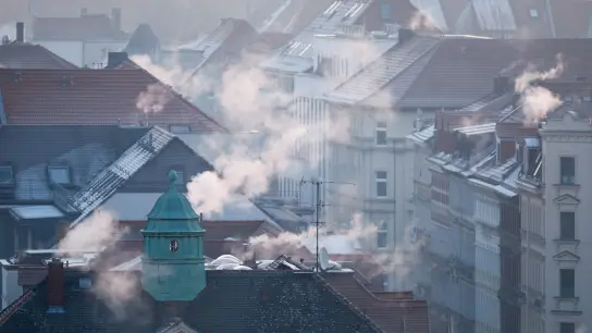 Rauch strömt aus Kaminen auf Dächern von Mehrfamilienhäuser. (Foto: Jan Woitas/dpa)