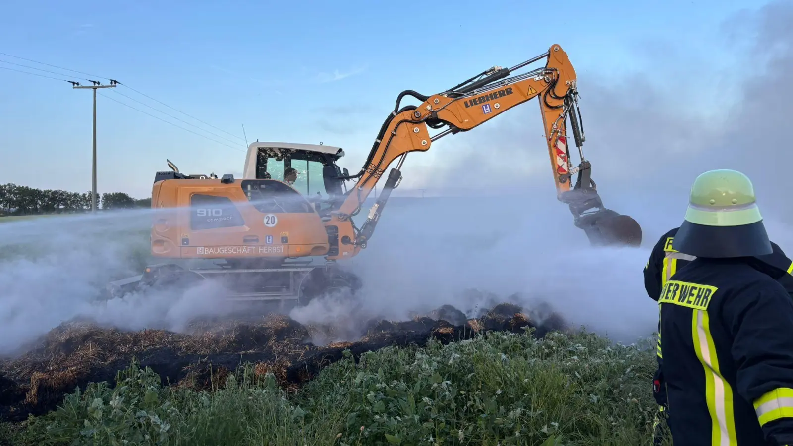 Mit Hilfe von schwerem Gerät zogen die Einsatzkräfte den Strohhaufen bei Markt Nordheim auseinander, um an die Glutnester zu kommen. Eine rauchige Angelegenheit. (Foto: Kreisfeuerwehrverband)