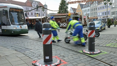 Zu den Hauptverkehrszeiten müssen Sicherheitsmitarbeiter neben dem Augsburger Christkindlesmarkt jede Stunde dutzendfach schwere Poller bewegen, damit die Straßenbahnen durchfahren können. (Foto: Malin Wunderlich/dpa)