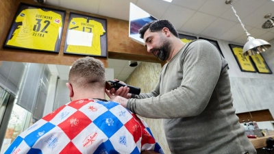 Friseur Taner Dogan schneidet in seinem Salon in einer Netto-Filiale einem Kunden  die Haare. (Foto: Bernd Thissen/dpa)