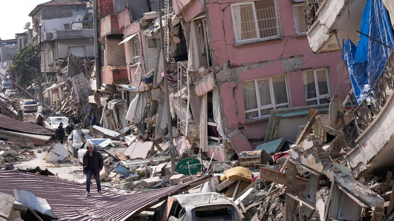 Ein Mann geht Anfang März über die Trümmer eingestürzter Gebäude in Hatay: Die Zahl der Todesopfer in der Türkei ist nach den Erdbeben  nochmals gestiegen. (Foto: Hussein Malla/AP/dpa)