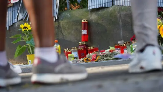 Menschen stehen in Dortmund vor einem Zaun, an dem mit Kerzen und Blumen des von der Polizei erschossenen Jugendlichen gedacht wird. (Foto: Gregor Bauernfeind/dpa)