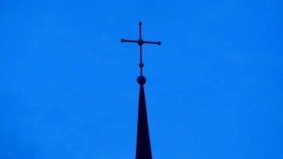 Kreuz einer evangelisch-lutherischen Kirche in der Abenddämmerung. (Foto: Friso Gentsch/dpa)