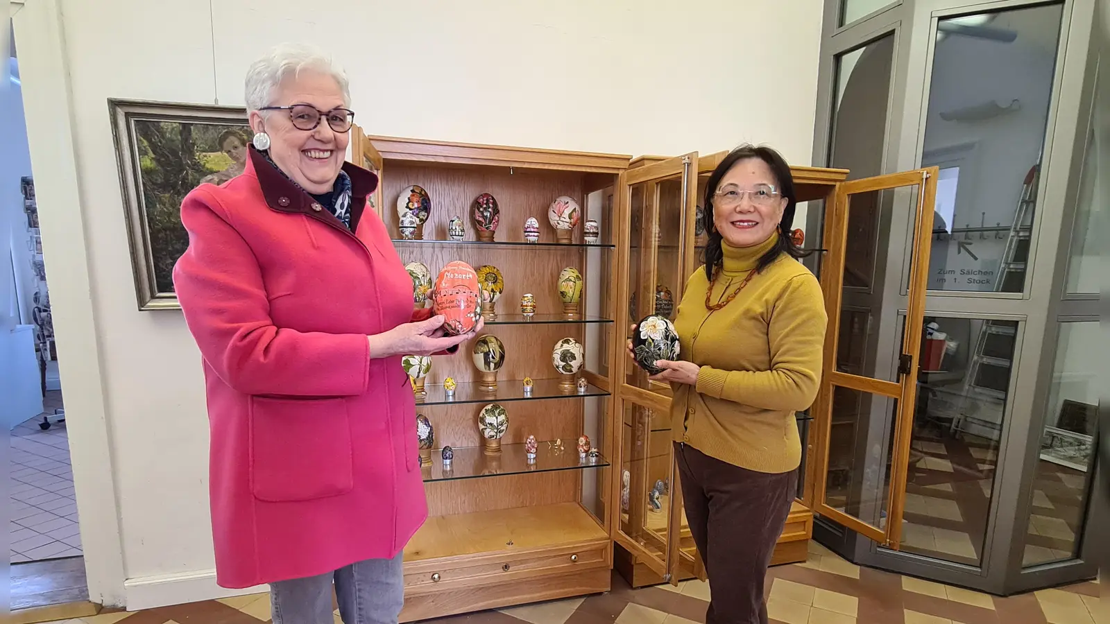 Die Kunstliebhaberin Marga Ortner (links) hat einen Großteil ihrer Kunsteier-Sammlung dem Doerfler-Museum überlassen. Sie füllen zwei Vitrinen, die ab sofort zur Dauerausstellung gehören, worüber sich Leiterin Hai Yan Waldmann-Wang sehr freut. (Foto: Margit Schwandt)