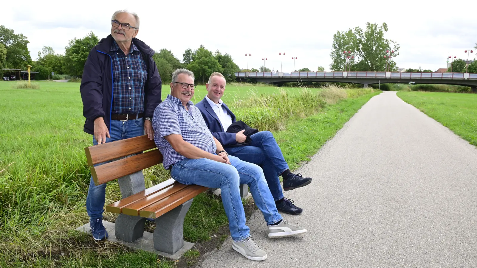 Peter Heinzel (Mitte), der Vorsitzende der Siedlergemeinschaft, und OB Thomas Deffner (rechts) sitzen auf der neuen Bank Probe. Heinzels Vize Reinhard Fichtner war bei der Übergabe im Bürgerpark dabei. (Foto: Jim Albright)